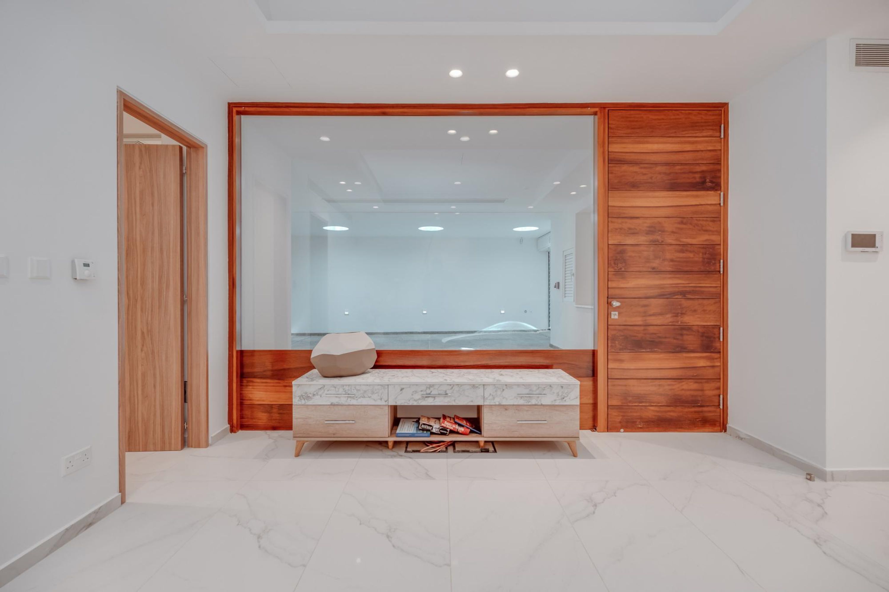 Un bagno moderno con un mobile lavabo in marmo, una porta in legno e uno specchio grande.