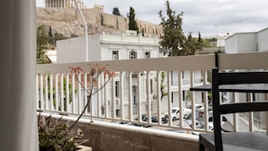 A balcony with a view of ancient ruins, a white building, and parked cars. - Deco Marble Apt With Acropolis View (Athens)