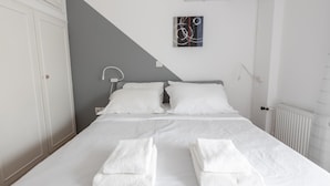 A neatly made bed with white linens and two folded towels on the bed. - Deco Marble Apt With Acropolis View (Athens)