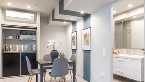 Une cuisine moderne dotée d’appareils électroménagers intégrés, un coin repas avec une table et des chaises, et une salle de bain avec un grand miroir et un lavabo.