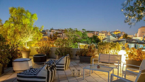 Une terrasse sur le toit, aménagée avec des sièges, des plantes en pot et offrant une vue sur la ville.
