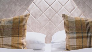 Un lit avec deux oreillers, l’un à carreaux et l’autre uni, blanc, adossé à un mur à texture.