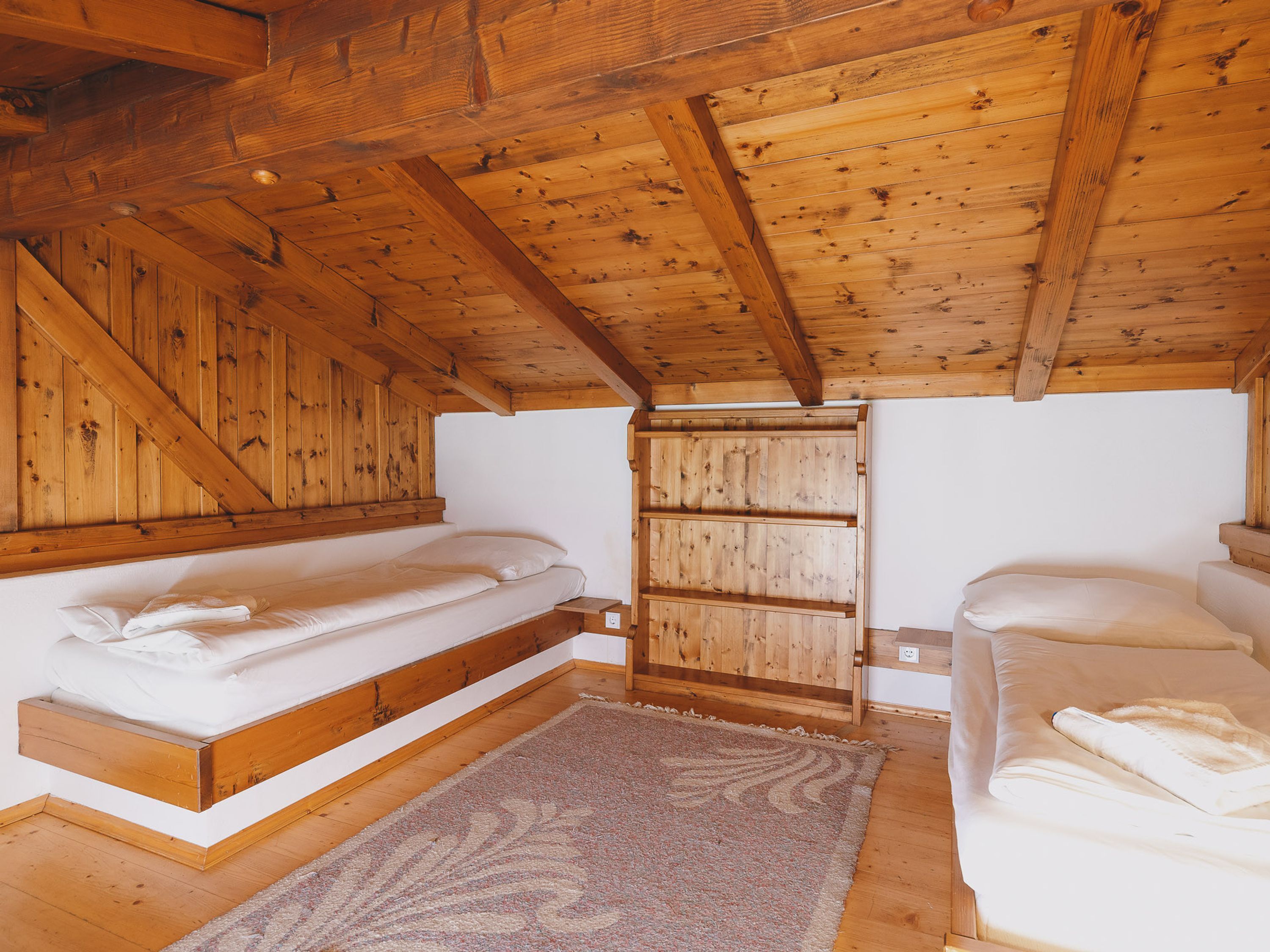 Een houten hutje met twee stapelbedden, een houten deur en een vloerkleed.