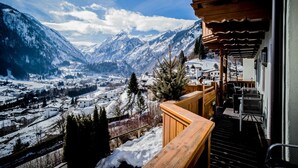 A wooden balcony with a view of a snow-covered mountain town. - Landhaus Lodges Kaprun - Johann (Kaprun)