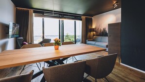 Un espace repas moderne avec une table en bois, des chaises, une plante en pot et un canapé.