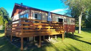 Une maison en bois à deux étages, dotée d’un balcon, d’une fenêtre et d’une porte.