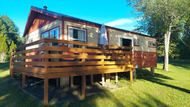 A two-story wooden house with a balcony, a window, and a door. - Twin Bay Resort Cabin #4 (Tomahawk)