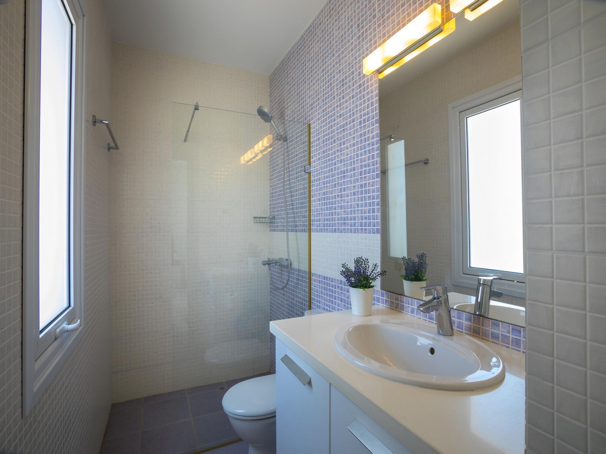 A modern bathroom with a shower, toilet, and sink.