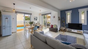 A spacious living area with a sofa, TV, and dining table. - Villa Kalimera in Protaras (Paralimni)