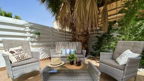 A patio area with wicker furniture, a glass coffee table, and a decorative plant arrangement. - Villa Kalimera in Protaras (Paralimni)