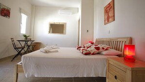 A bedroom with a bed, bedside table, and a nightstand with a red lamp.