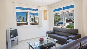 Una sala de estar moderna con un sofá, una mesa de centro de vidrio y una televisión.