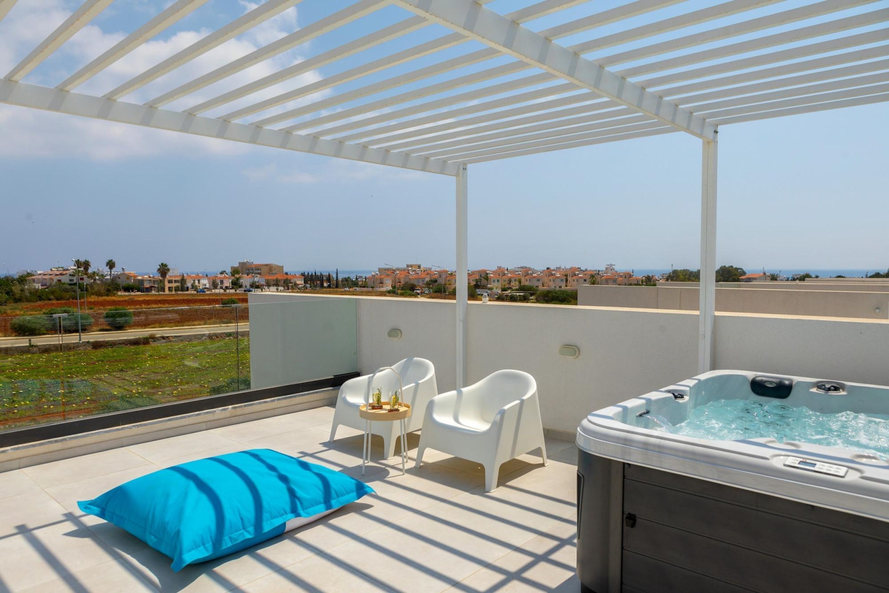 Een terras op het dak met een hottub, witte stoelen en een blauw kussen.