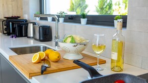 Una cocina moderna con un colador, limones, una botella de vino y una tabla de cortar.