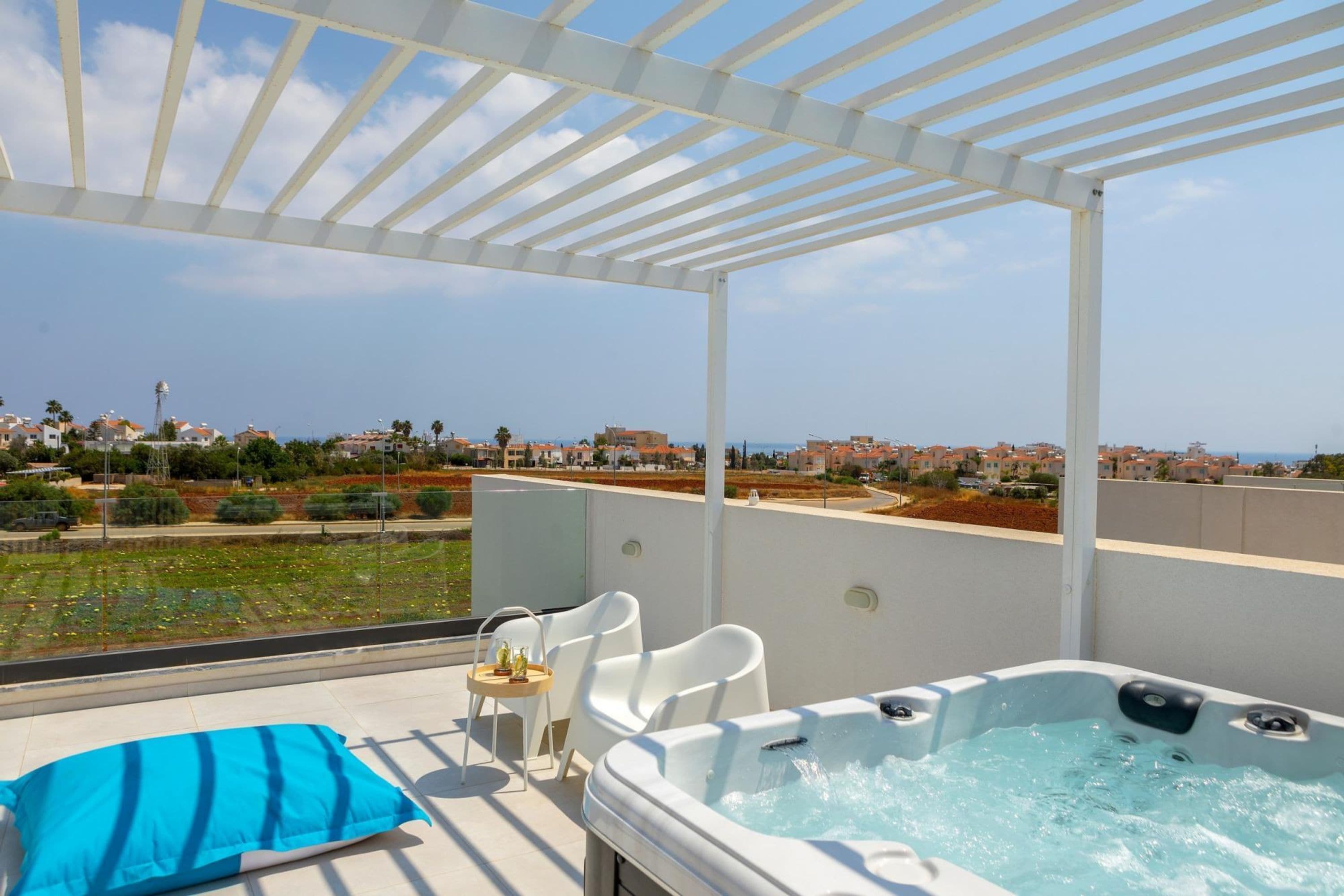 Eine Dachterrasse mit Whirlpool, Liegestühlen und Blick auf die Skyline der Stadt.