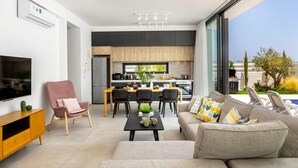 Una sala de estar moderna con un sofá, un televisor y un comedor con sillas y una mesa.