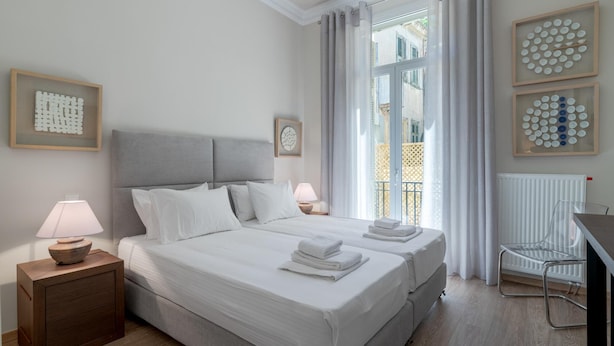 A hotel room with two beds, a desk, a chair, and artwork on the walls. - Historic Plaka s Deluxe Apartment (Athens)