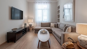 A modern living room with a flat-screen TV, a sofa, a coffee table, and a lamp. - Historic Plaka s Deluxe Apartment (Athens)