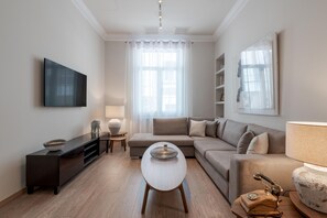 Een moderne woonkamer met een flatscreen televisie, een bank, een salontafel en een lamp.