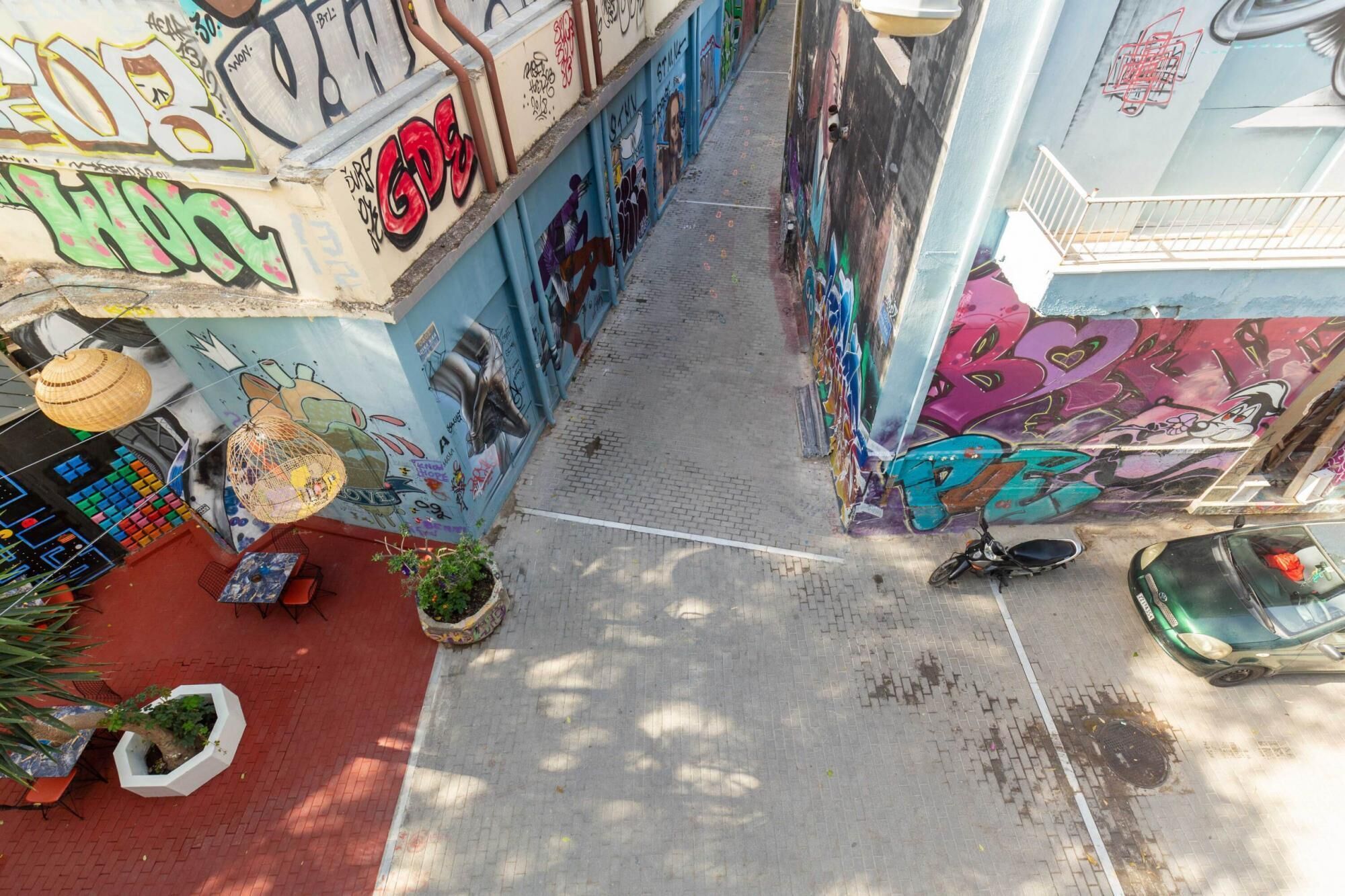 An alleyway with colorful graffiti on the walls, a narrow path, and a parked scooter.