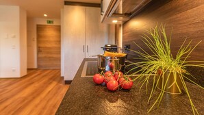 A kitchen counter with a potted plant, a pot of spaghetti, and some tomatoes. - Tevini Boutique Suites - Apartment Earth (Zell am See)