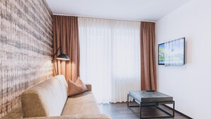 A modern living room with a sofa, a coffee table, and a TV mounted on the wall. - Alpine City Living - TOP 11 (Zell am See)