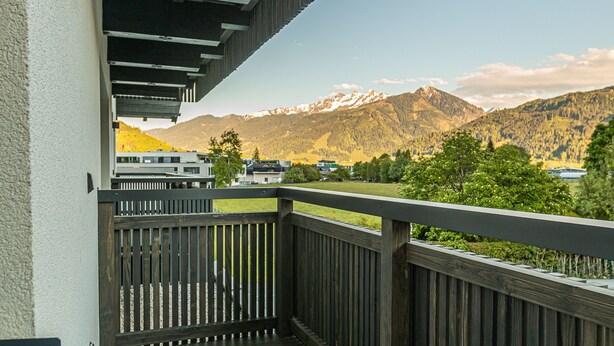 Un balcon avec vue sur les montagnes et un bâtiment en arrière-plan.