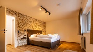 Une chambre à coucher avec un lit, une porte, un luminaire fixé au mur et une fenêtre.