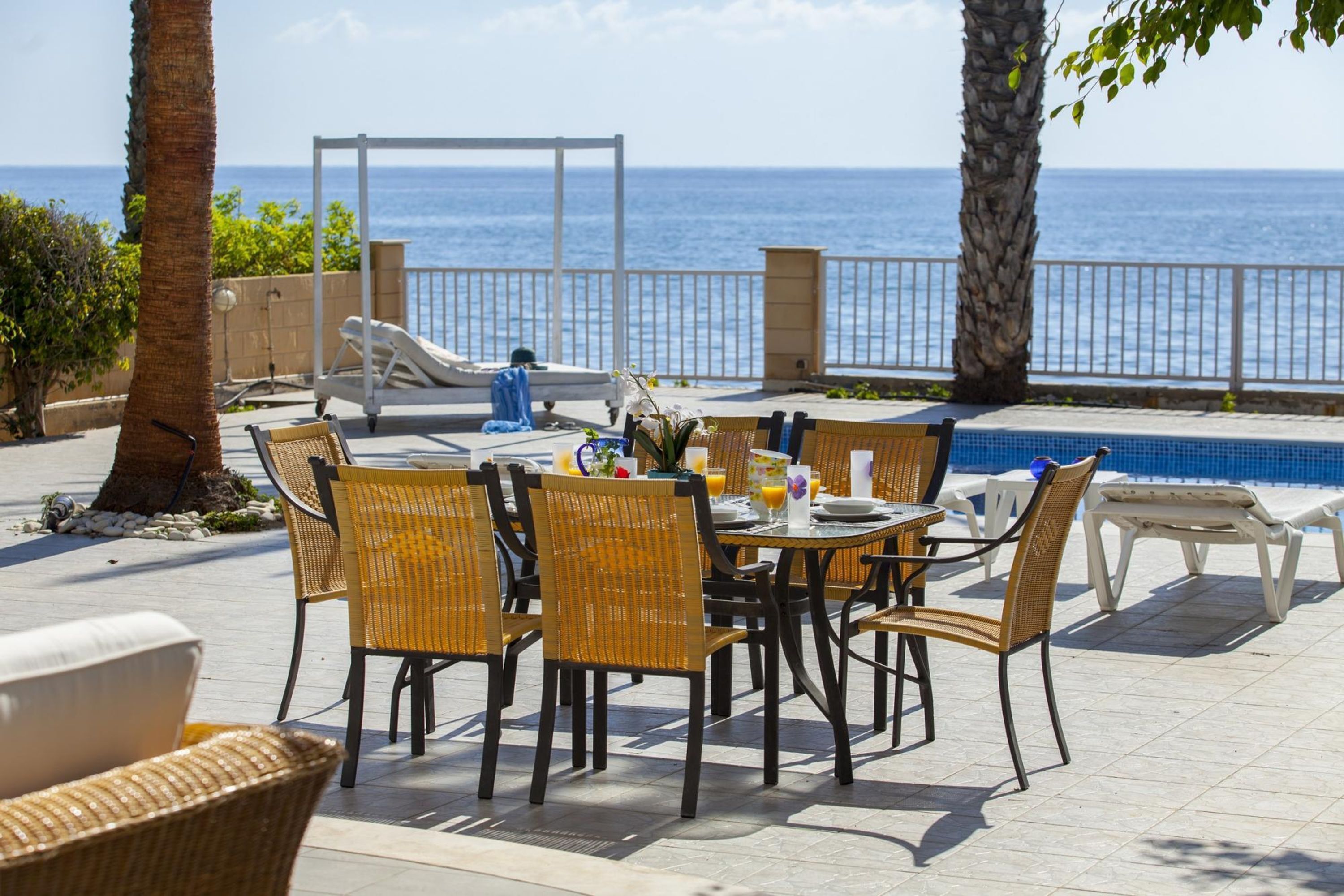 A patio area with a pool, dining table, chairs, and a lounge chair.