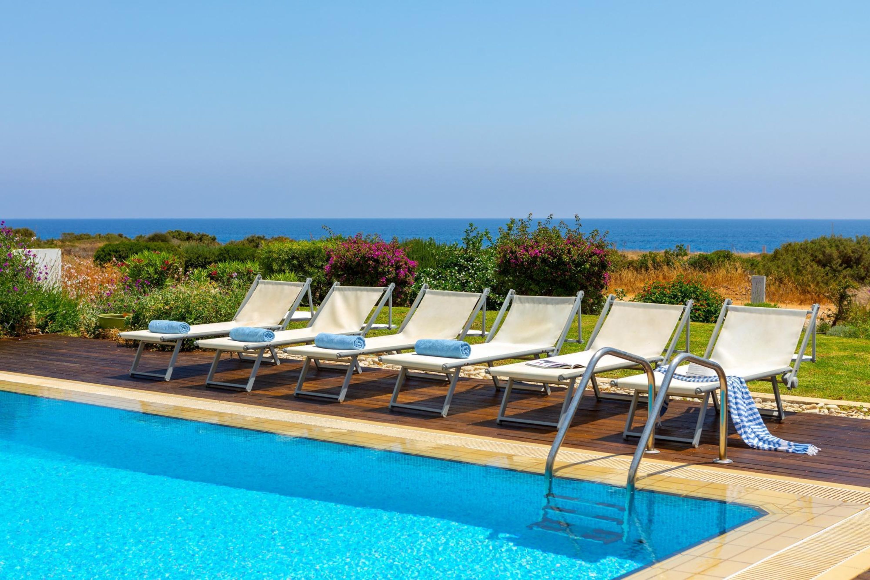 A poolside area with lounge chairs and a view of the sea.
