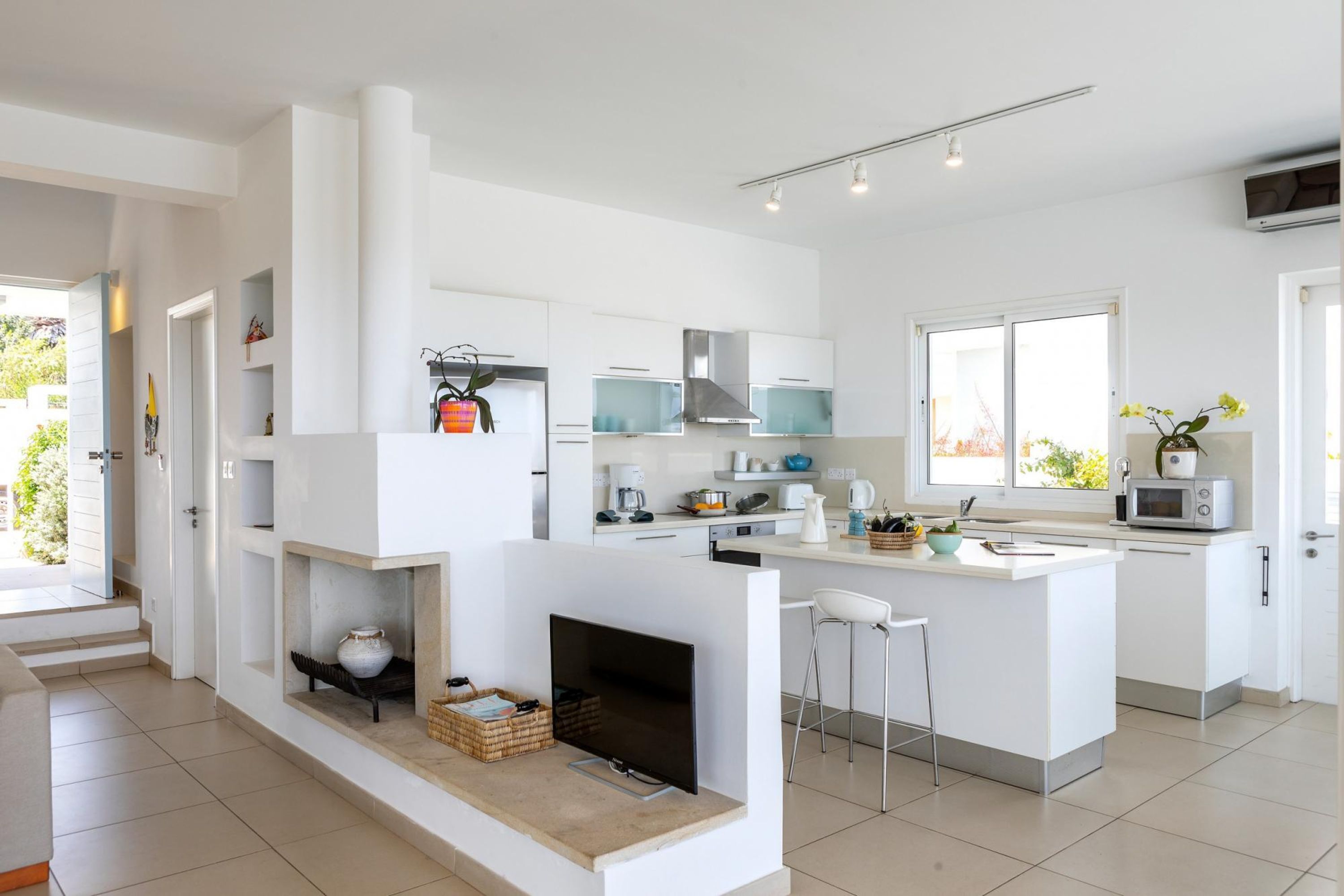 Una cucina moderna con mobili bianchi, un'isola centrale e un camino integrato.