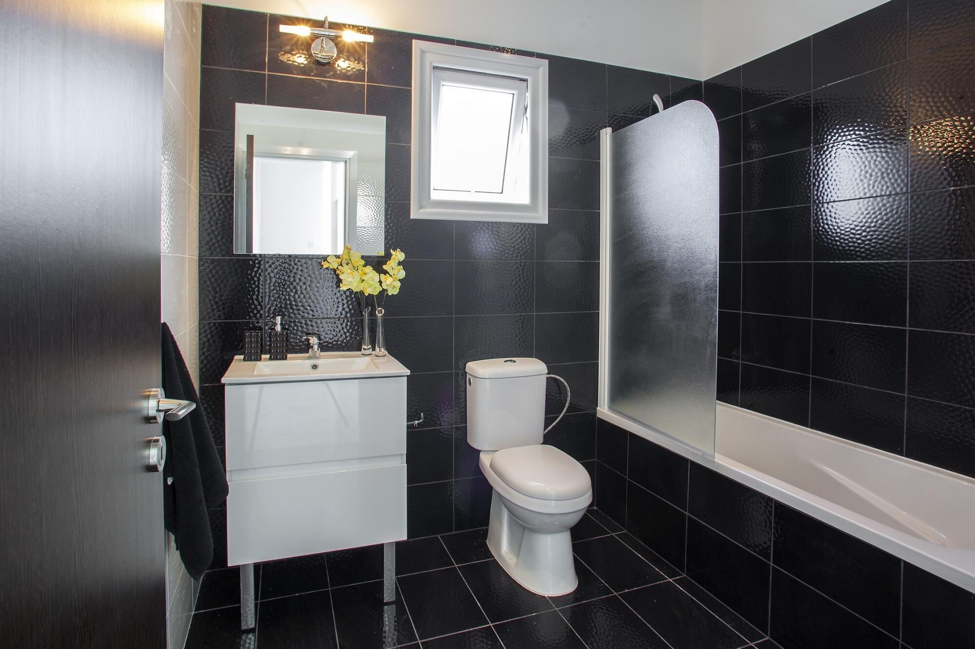 Une salle de bain avec un lavabo blanc, des toilettes et une baignoire.