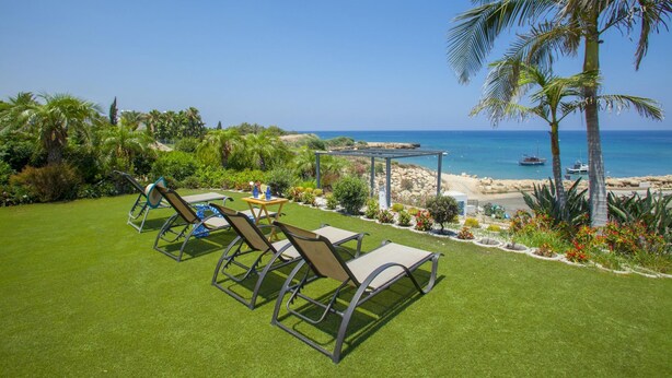 A well-maintained lawn with outdoor furniture, a gazebo, and a view of the ocean and boats. - Protaras Coast Panorama (Paralimni)