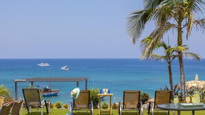 A terrace with a view of the sea, featuring a table with chairs, a small table with drinks, and a palm tree. - Protaras Coast Panorama (Paralimni)