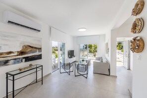 A spacious living area with a large window, a glass coffee table, and a sofa.
