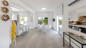 Una cocina moderna con armarios blancos, una isla central con taburetes y un comedor con una mesa redonda y sillas.