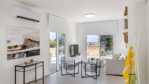 Una sala de estar moderna con un ventanal grande, un televisor de pantalla plana y un sofá.