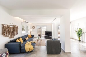 A modern living room with a sofa, armchair, and a television.