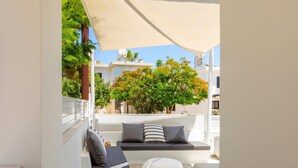 A modern outdoor seating area with a white sofa and cushions, a white round table, and a large canopy providing shade. - Protaras Rose By The Sea Villa (Paralimni)