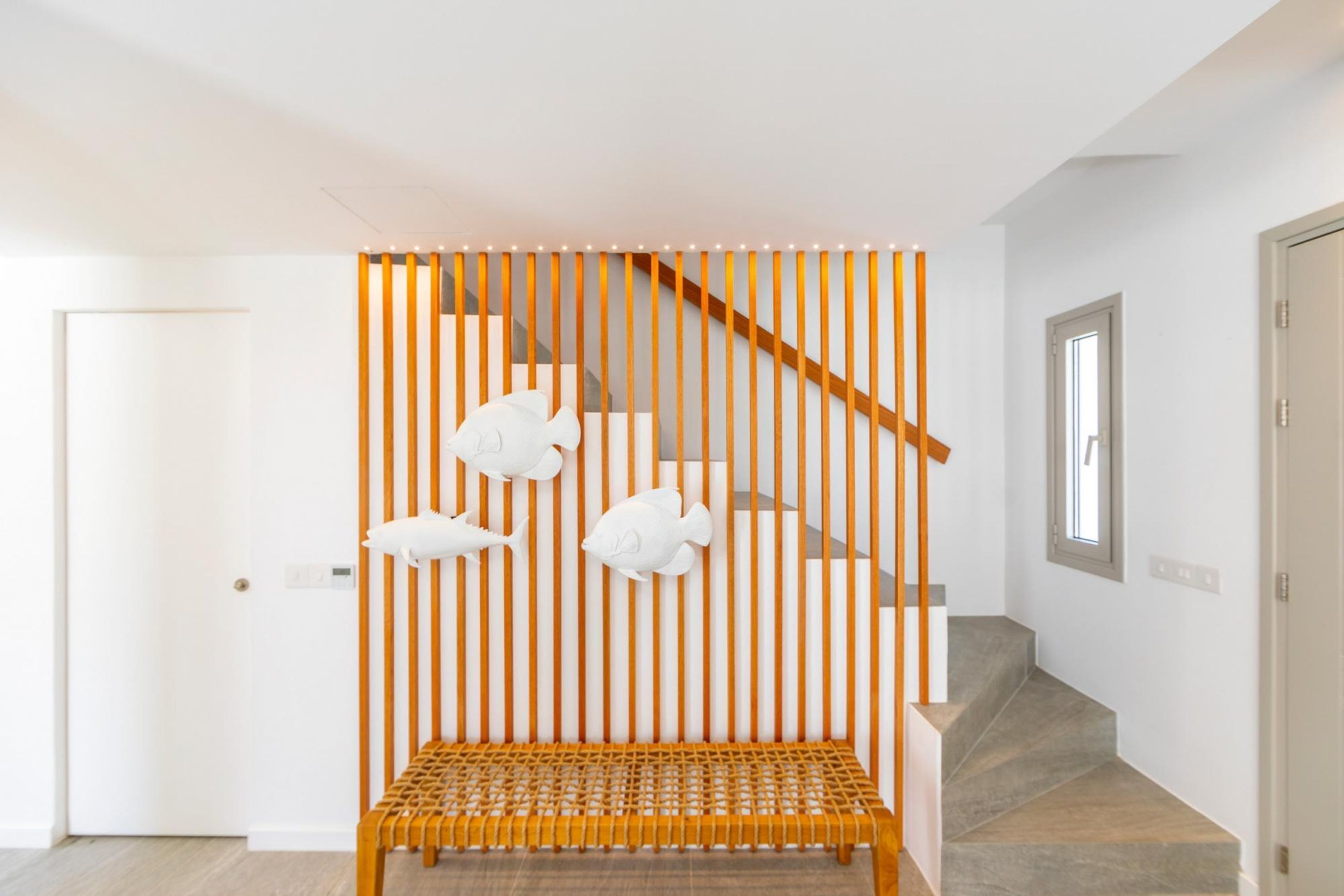 A staircase with a wooden handrail and a bench at the bottom.