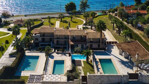 Eine großzügige Villa mit mehreren Schwimmbecken, einem gepflegten Garten und Meerblick.