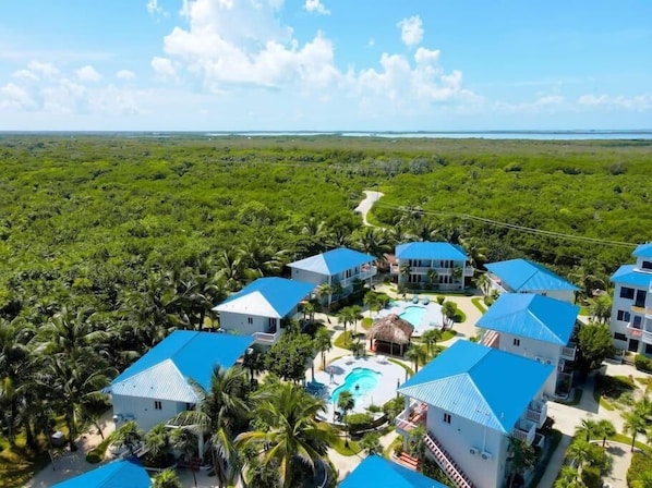 A resort with multiple buildings, a swimming pool, and a lush green landscape. - 1BR Seaside Casita @ Sapphire Beach Resort (San Pedro Town)