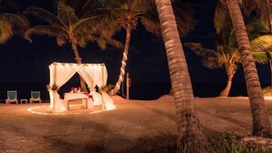 A beachside tent with a table and chairs, surrounded by palm trees. - 1BR Seaside Casita @ Sapphire Beach Resort (San Pedro Town)