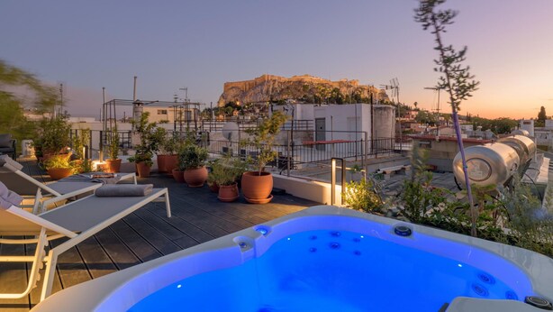 Una terraza en la azotea con jacuzzi, sillones de descanso y plantas en macetas.