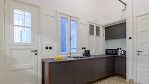 Cocina compacta con pileta, microondas y tetera. Hay dos ventanas y una puerta.