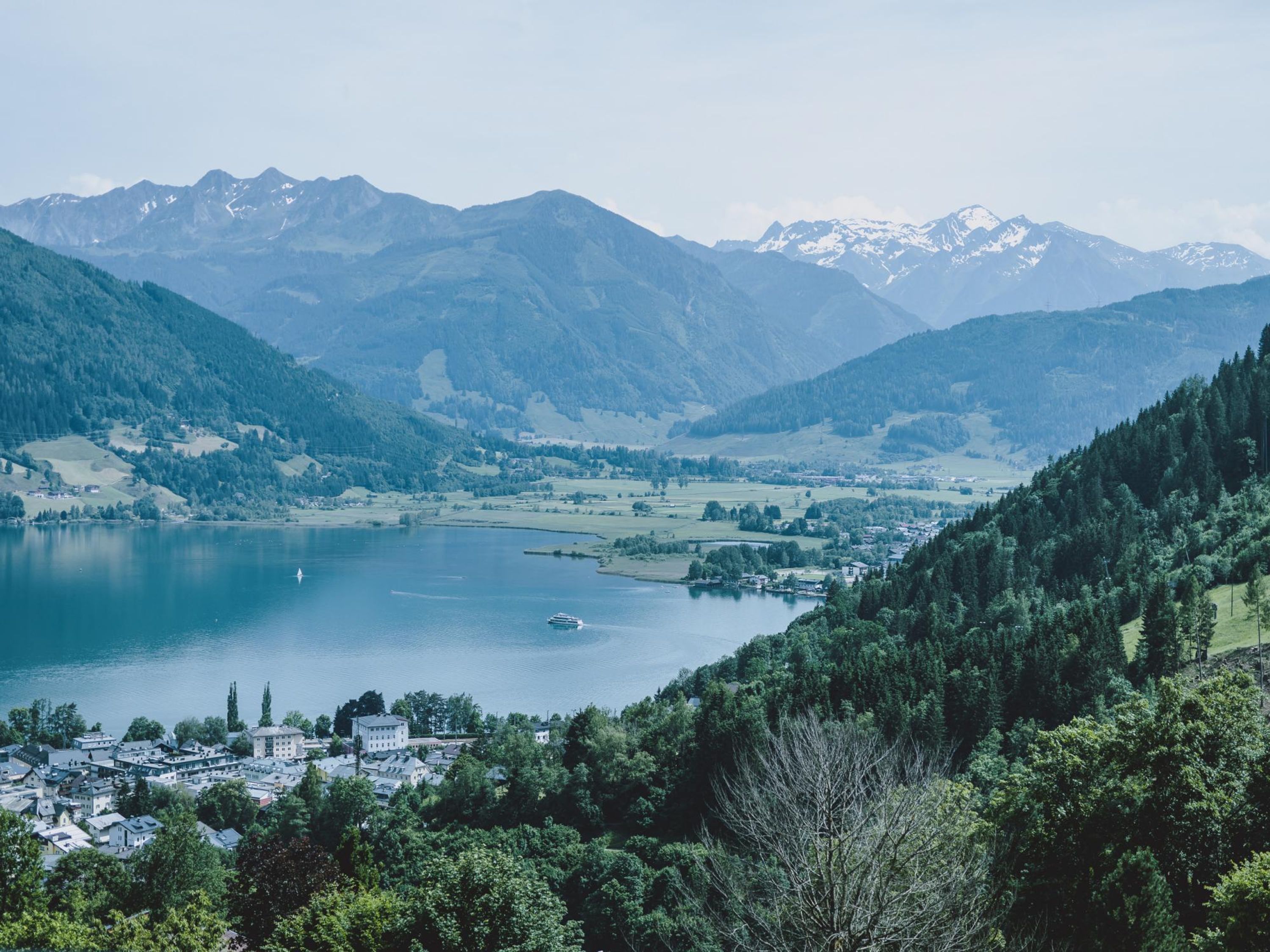 Un pueblo a orillas del lago con edificios, un bote y montañas al fondo.