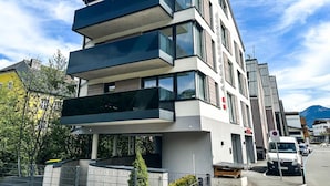 Un edificio moderno de varios pisos, con balcones, ventanas amplias y cielo despejado.