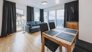 Una sala moderna con una mesa de comedor de madera, sofá gris y cortinas negras.