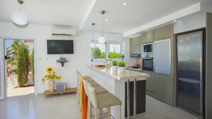 A modern kitchen with a central island, built-in appliances, and a large window. - Villa Lavender in Ayia Napa (Sotira)