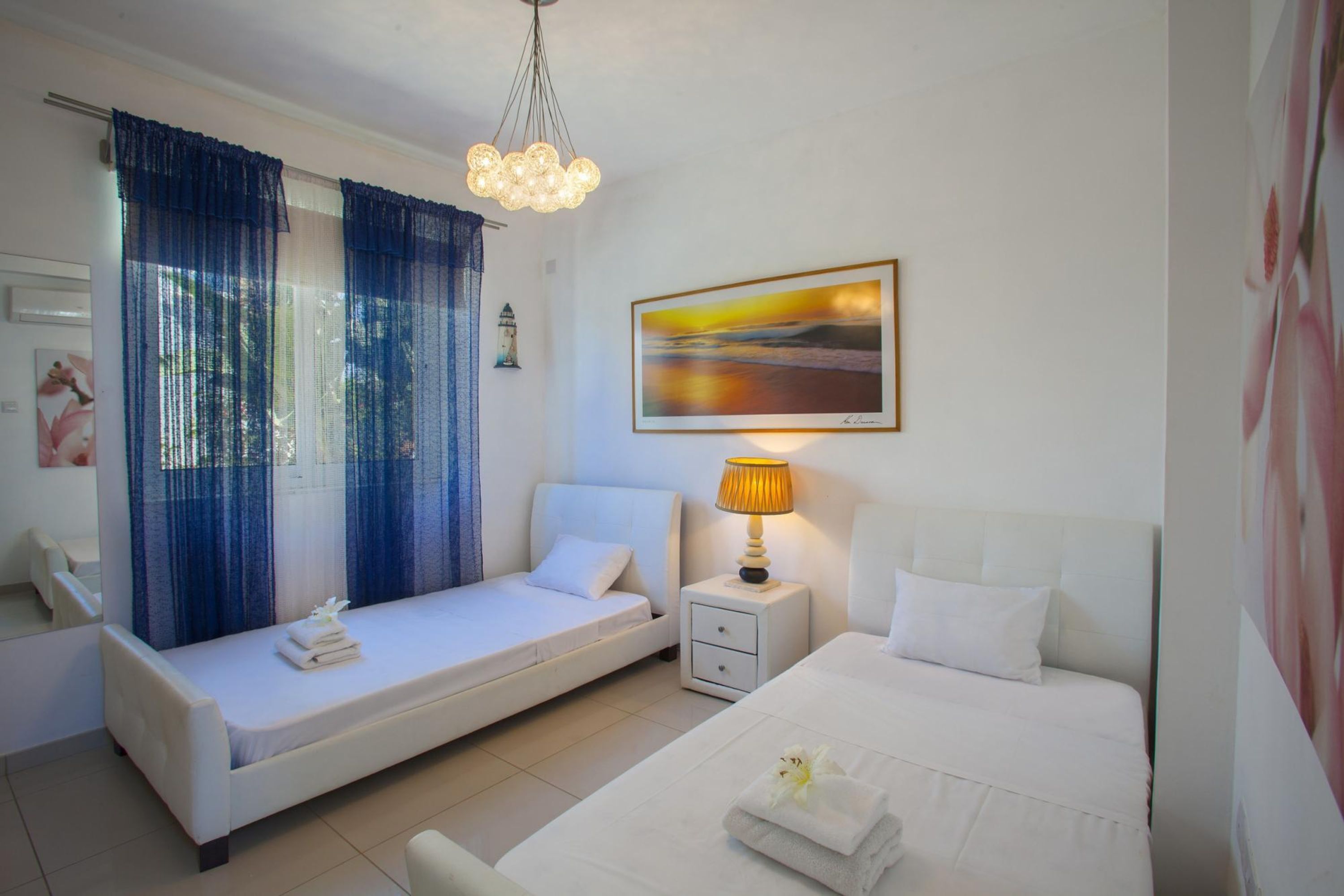 Een hotelkamer met een bed, een slaapbank, een nachtkastje met een lamp en een schilderij aan de muur.
